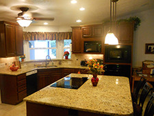 A kitchen with center island, dark cabinets and lighting fixtures