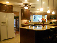 A kitchen with center island, dark cabinets and lighting fixtures